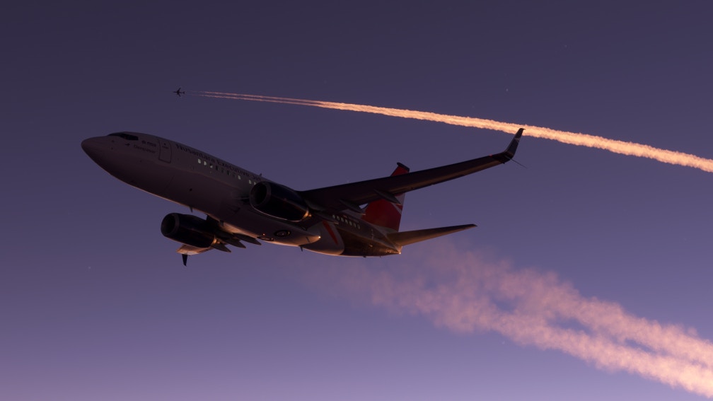 A Boeing 737 flies below another aircraft banking to the right at dusk